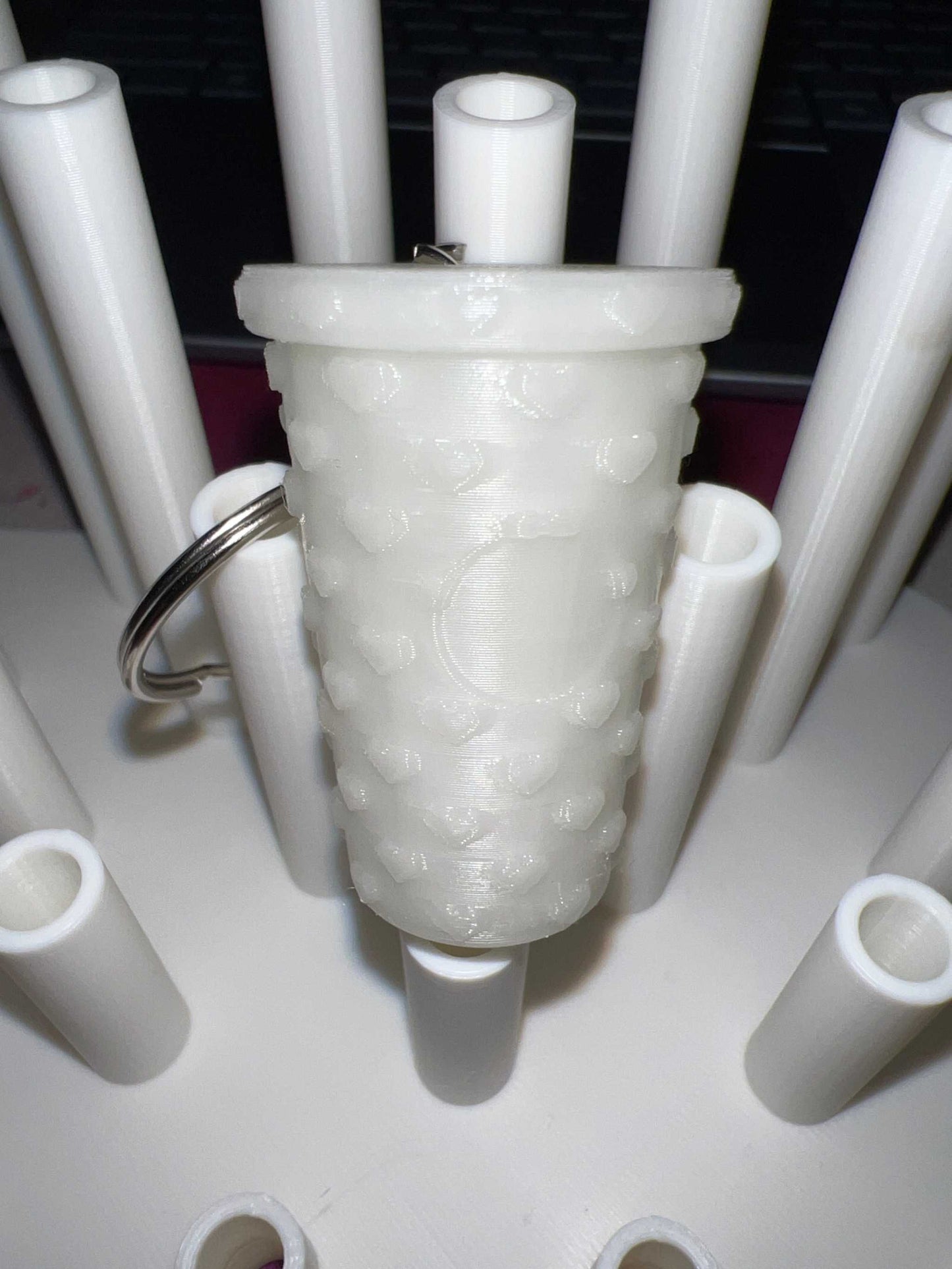 Glow in the dark tumbler shaped keychain with textured surface and attached metal ring