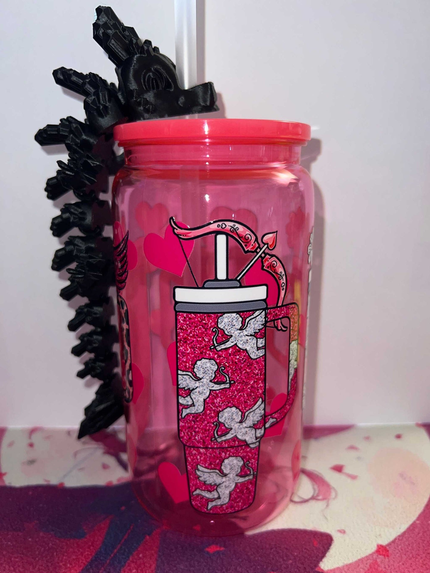 Pink cup with cupid design and black dragon straw topper attached to white straw