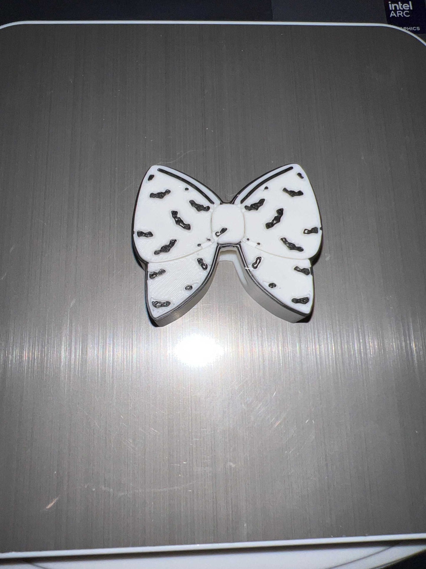 White bat bow straw topper with black bat silhouettes design on a gray surface