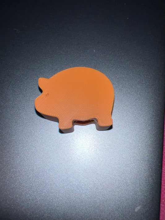Orange pig-shaped object labeled Piggy’s on a dark surface