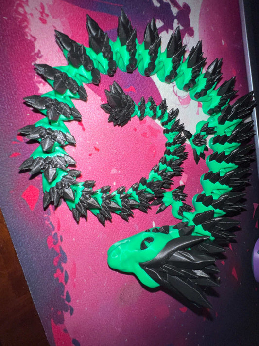 coiled XL dragon figure with green and black segmented body and spiked head on pink surface