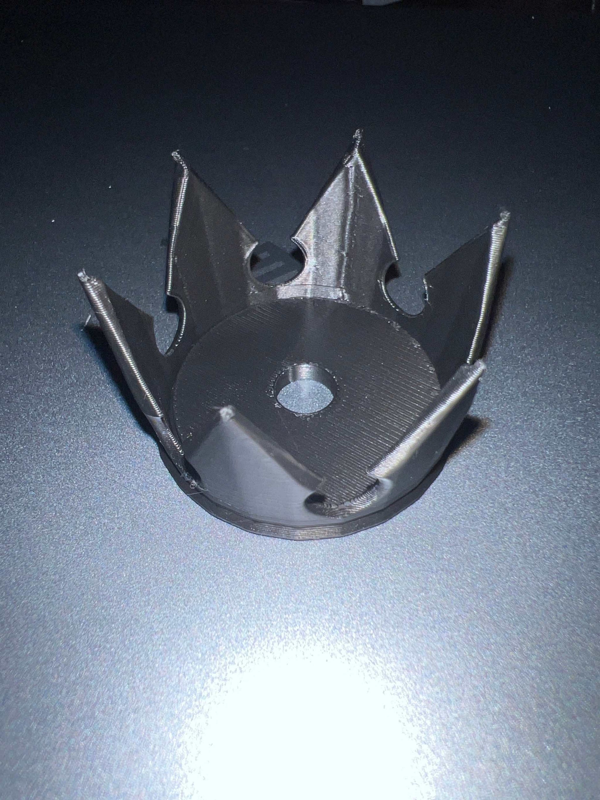 Black plastic crown-shaped straw topper with central hole for inserting straw