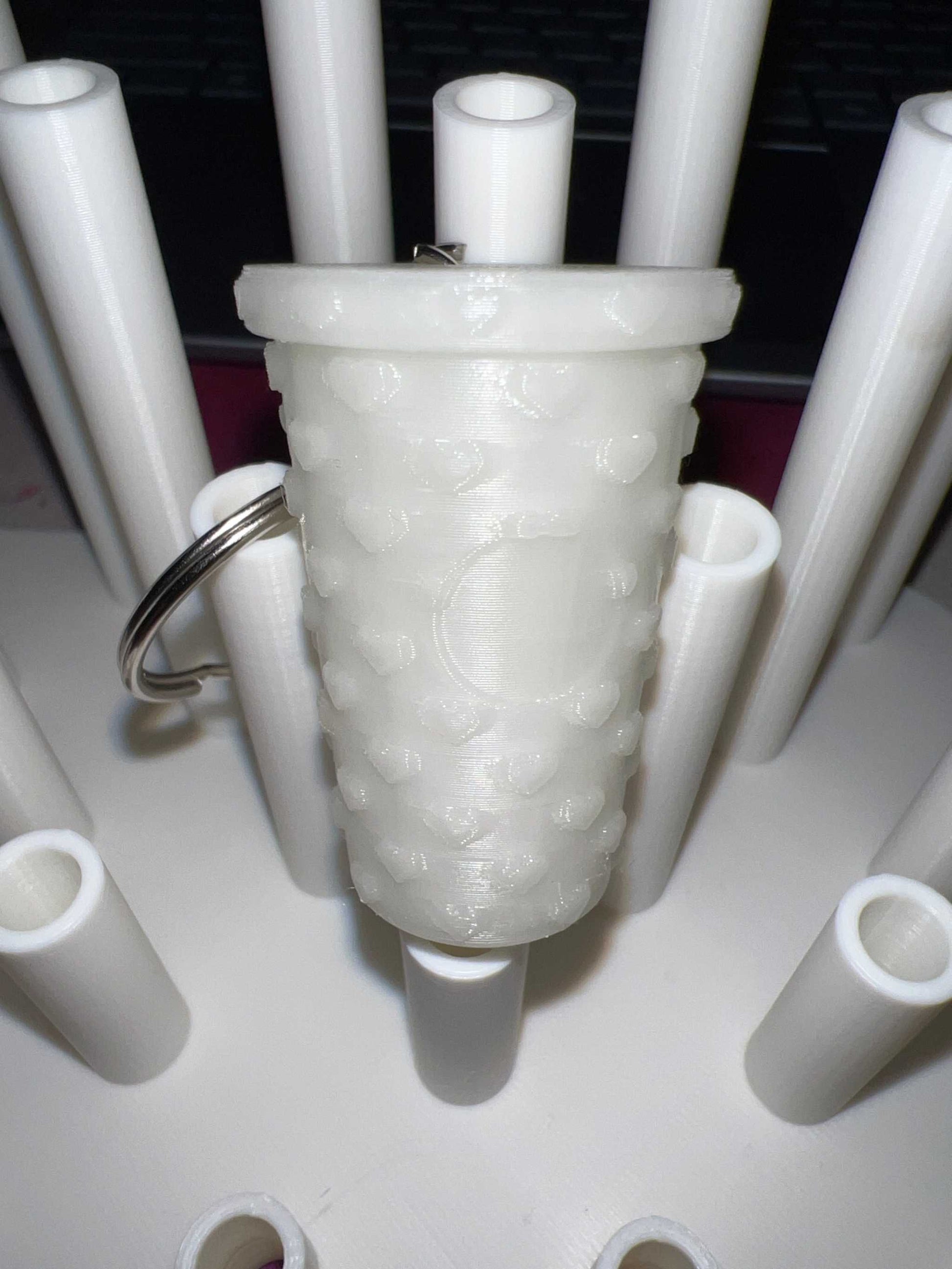 Glow in the dark tumbler shaped keychain with textured surface and attached metal ring
