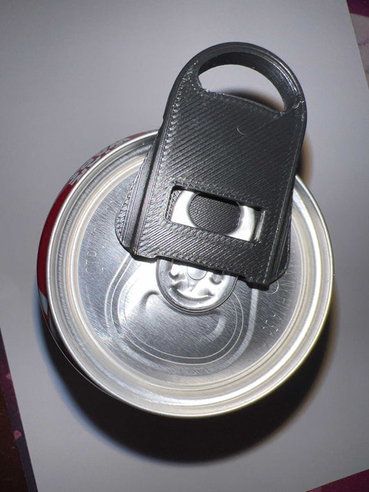 Black can soda lid opener attached to a silver soda can top
