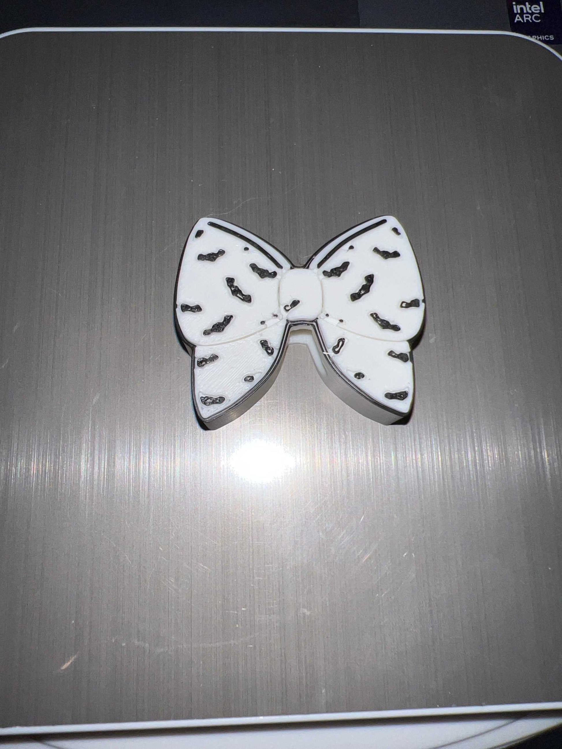 White bat bow straw topper with black bat silhouettes design on a gray surface