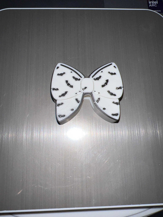 White bat bow straw topper with black bat silhouettes design on a gray surface