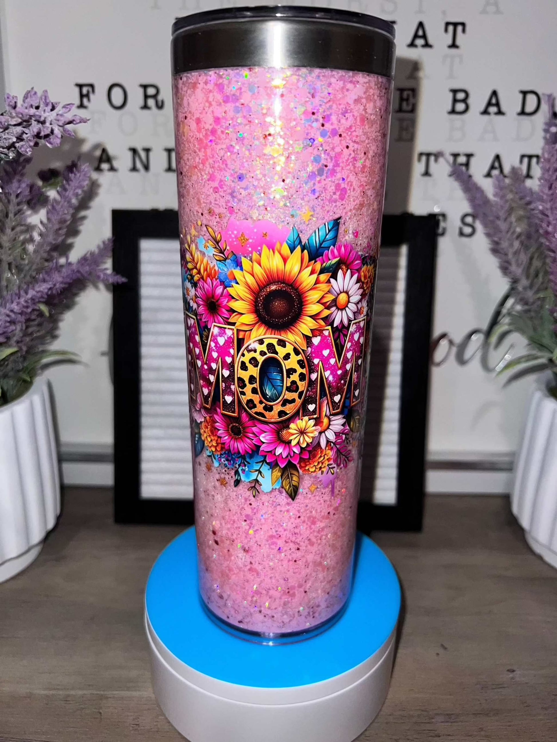 Pink glitter tumbler with floral design and "MOM" text.