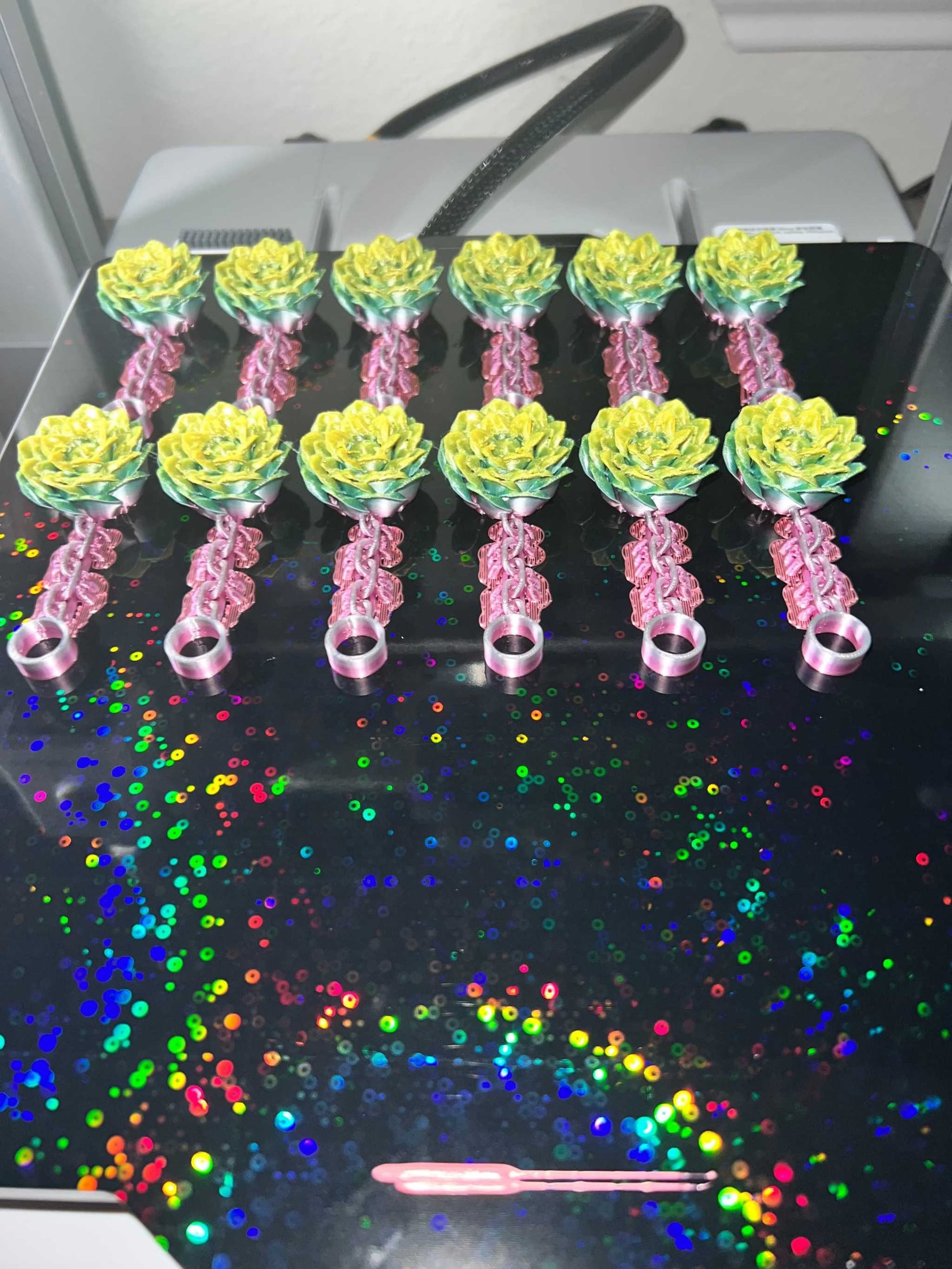 Set of colorful peony straw stoppers arranged on a reflective surface with rainbow sparkles