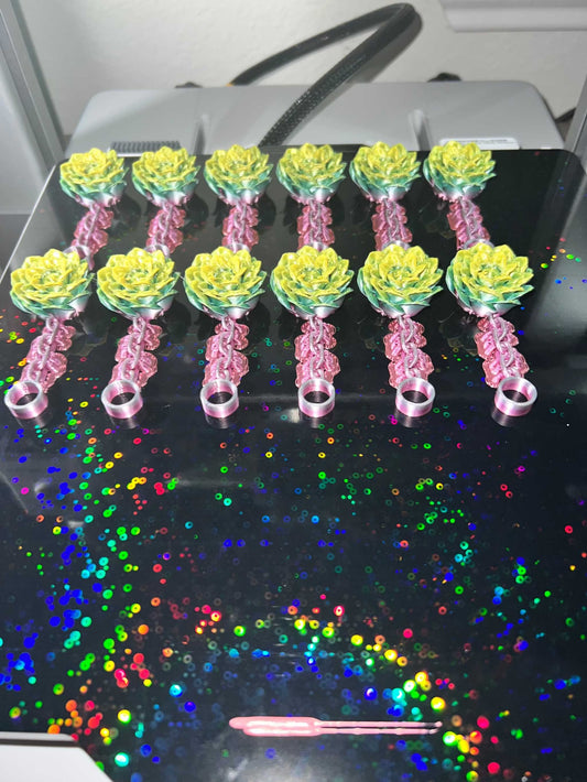Set of colorful peony straw stoppers arranged on a reflective surface with rainbow sparkles