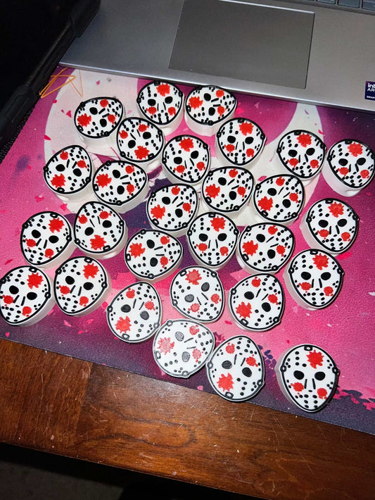 Jason straw toppers featuring horror-themed mask designs with red blood splatters arranged on a surface next to a laptop.