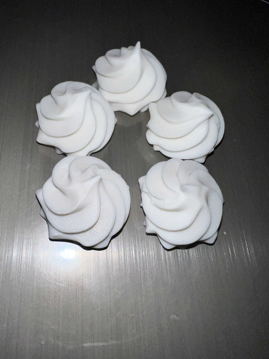 Five white whipped cream lid toppers arranged on a gray surface for decorative use on drink lids.