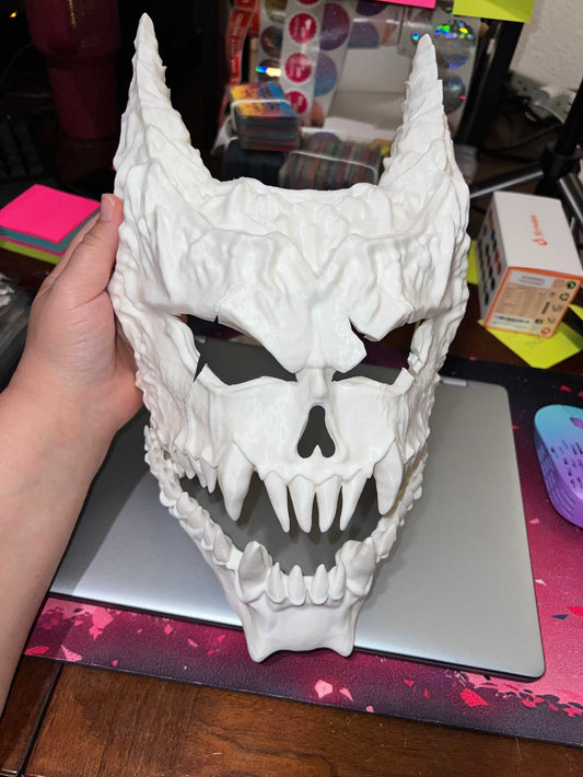 White Kaiju Num 8 mask with movable mouthpiece and horned design held over laptop