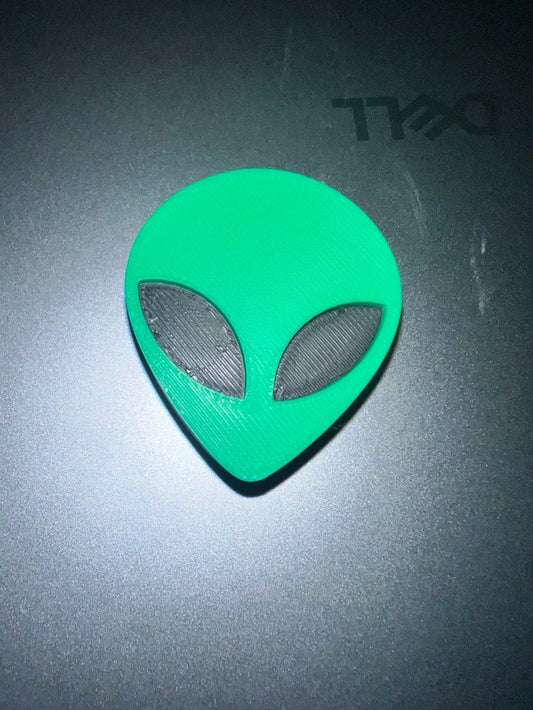 Alien head straw topper in green with black eyes on dark surface