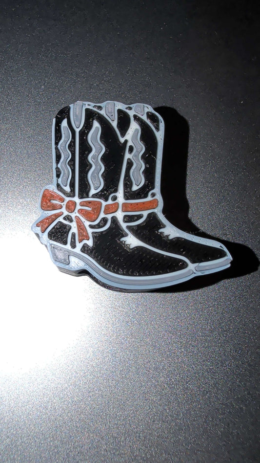 Black and white country boots pin with red bow detail on dark background