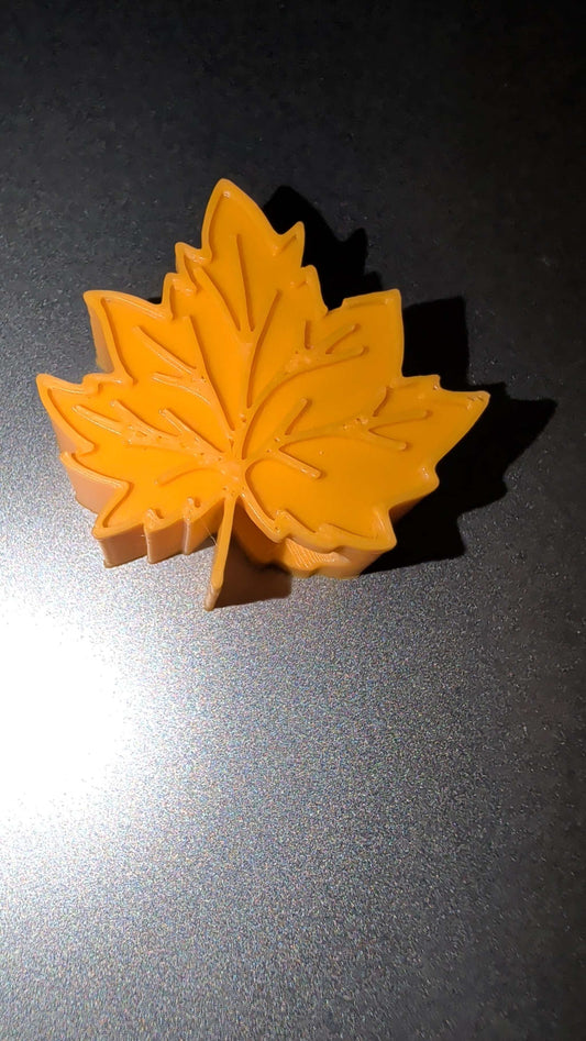 Orange leaf-shaped silicone straw stopper on dark surface