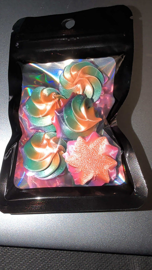 Pack of five rainbow mini whipped lid toppers in colorful swirl and star shapes inside a resealable black pouch