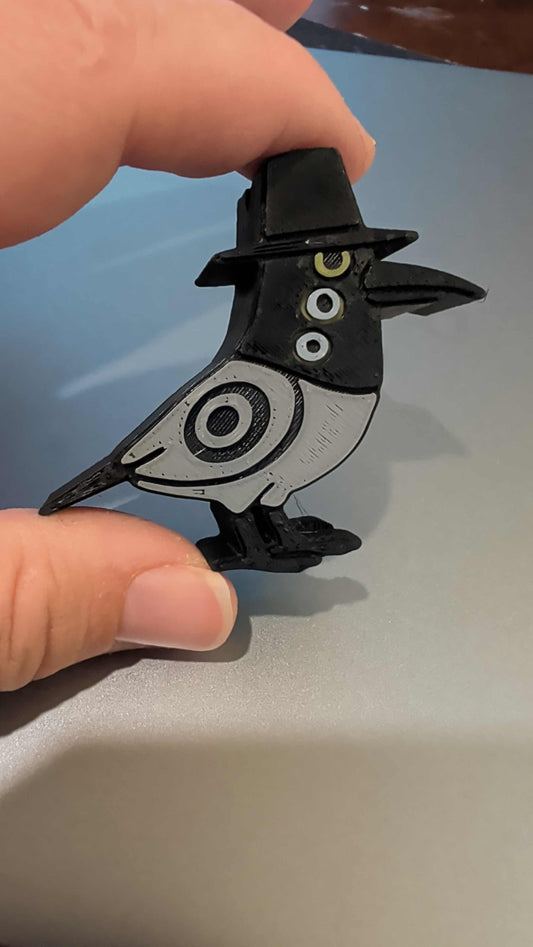 Hand holding a Bird KPOP figurine wearing a black hat with graphic black and white design
